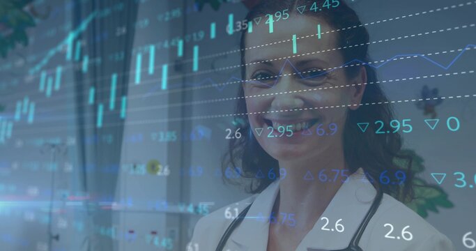 Standing doctor in lab coat, stethoscope, eyeglasses, viewing overlaid financial charts in clinic
