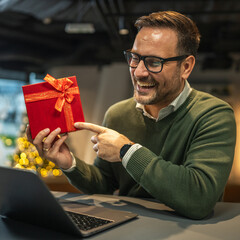 Man receiving gift during video call at home office