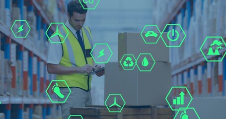 Scanning warehouse worker in hi-vis vest and tie checking tablet by wooden pallet, neon icons