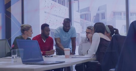 Discussing six colleagues leaning around meeting table, reviewing laptop papers in business attire