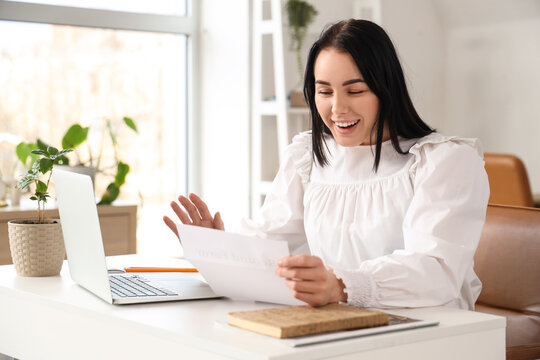 Happy businesswoman with refund form at table in office