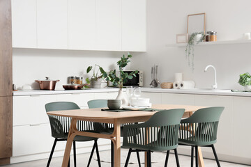 Interior of light kitchen with dining table, counters and plants