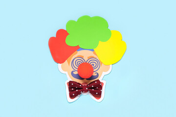 Funny clown's face made of paper, ball and bow tie on color background