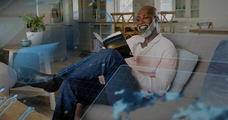 Mature man reading book on sofa, tech map overlay drifting causing page turn and sparking thought - Powered by Adobe