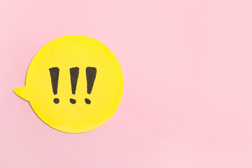 Obraz premium Yellow speech bubble with exclamation marks on pink background