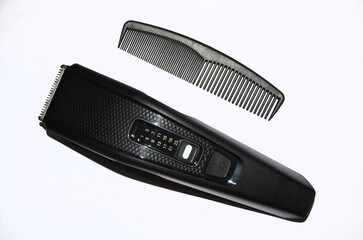 Hair clipper and flat comb on a white background.