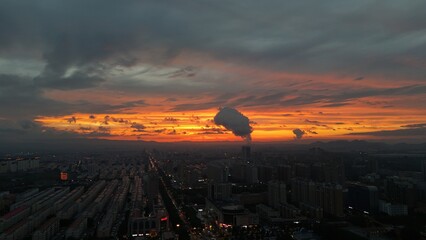 Aerial view of city neon under the sunset and fiery clouds