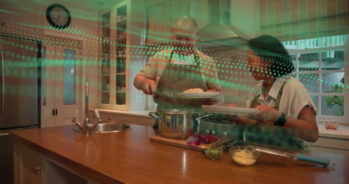 Man lifting pasta from pot, woman holding plates on island, green overlay guiding food plating