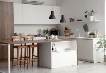 Interior of modern kitchen with counters, table and lamps