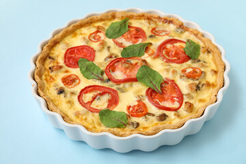 Delicious tomato tart with spinach leaves on blue background