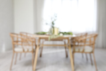Blurred view of elegant table setting with beautiful flowers and candles in light dining room