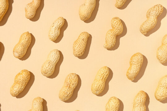 Many unpeeled peanuts on beige background