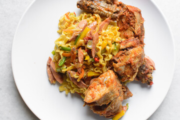 Overhead view of egg noodles with peppers, sausage and peppered chicken on a white plate, top view of egg noodles with spicy chicken
