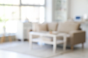 Blurred view of living room with soft couch, table and window