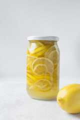 lemon cheong in a glass jar on a white background, korean lemon cheong in a transparent jar, lemon slices in sugar syrup
