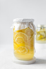 lemon cheong in a glass jar on a white background, korean lemon cheong in a transparent jar, lemon slices in sugar syrup