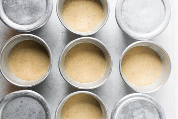 Overhead of moi moi mixture in silver pans, top view of nigerian bean pudding about to be steamed in steel pans, process of making nigerian moi moi