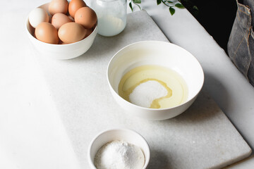 eggs and sugar in a white mixing bowl, mixing eggs and sugar by hand, process of making a cake