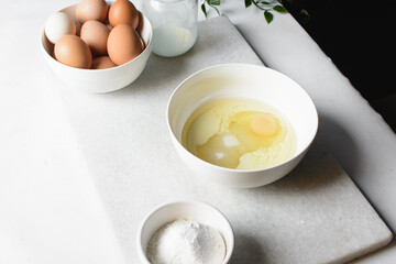 eggs and sugar in a white mixing bowl, mixing eggs and sugar by hand, process of making a cake