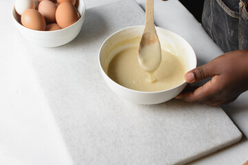 Overhead view of cake batter being mixed with a wooden spatula, process of mixing cake batter