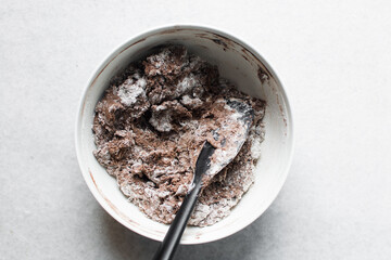 Overhead view of chocolate cookie dough being mixed in a white mixing bowl, process of making dark chocolate sugar cookies