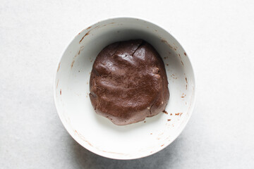 Overhead view of chocolate cookie dough being mixed in a white mixing bowl, process of making dark chocolate sugar cookies