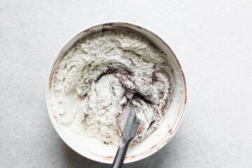 Overhead view of chocolate cookie dough being mixed in a white mixing bowl, process of making dark chocolate sugar cookies