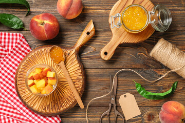 Jar of jam, bowl with peach pieces, rope and scissors on wooden background