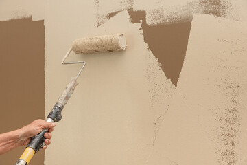 Man painting a brown wall tan