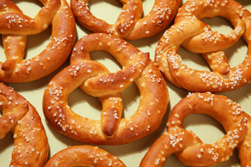 Many tasty salted pretzels on green background, closeup