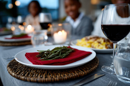 A beautifully arranged dining table featuring plates with herbs, red wine glasses, and soft candlelight, creating an inviting atmosphere for a special meal.