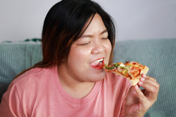Fat woman is eating pizza. She looks happy. Weight loss concept. Health care.