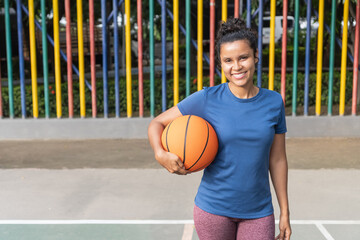 Fototapeta premium Smiling woman holding basketball standing on court