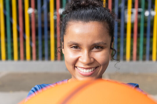 Smiling woman playing basketball, showing joy and active lifestyle