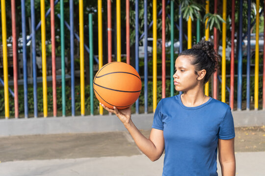 Woman basketball player holding ball looking focused outdoors