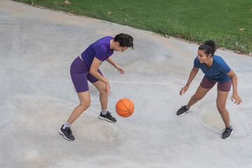 Women playing basketball outdoors enjoying teamwork and sport