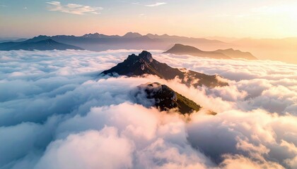 Aerial view of mountain peaks rising above a sea of clouds at sunrise, with a warm and serene atmosphere.