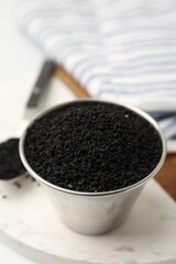 Aromatic black caraway in bowl and spoon on table, closeup