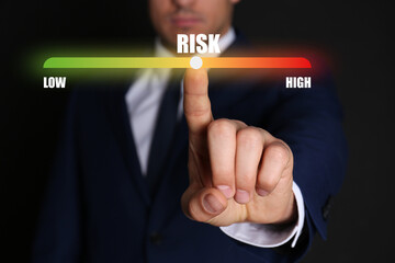 Man regulating level of risk on virtual screen against black background, closeup