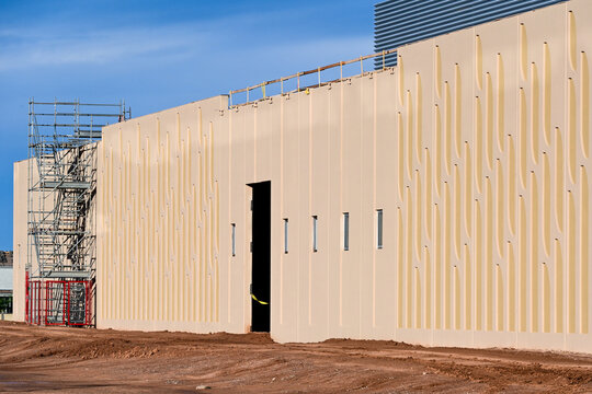 Prefabricated concrete wall panels forming a data center exterior with scaffolding nearby, illustrating modular construction methods and large scale digital infrastructure development