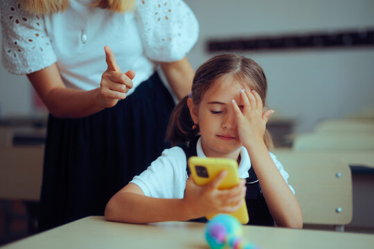 Teacher Scolding Student for Using Phone in her Class. Little girl breaking classroom rules checking her mobile 