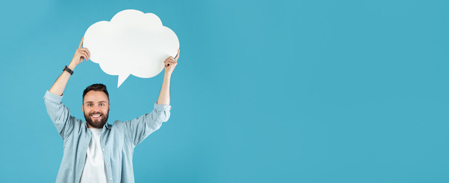 A man with a beard smiles brightly while holding a large blank speech bubble above his head. He stands against a solid blue background, conveying a fun and lively atmosphere.