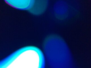 Abstract blue and cyan light flares with purple bokeh on a dark, blurry background, creating a vibrant, out-of-focus optical effect for overlays and designs