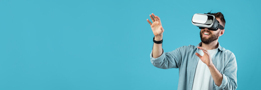 A man wearing virtual reality goggles is immersed in an interactive experience. He appears happy and is gesturing as if interacting with a virtual environment.