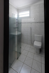 clean functional bathroom interior, white tile with blue accent border, pedestal sink and glass shower, practical small washroom design, bright hygienic toilet and basin, residential apartment rental