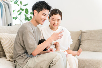 A couple of parents sitting on the sofa looking at their smartphones (apps, online applications, childcare support)