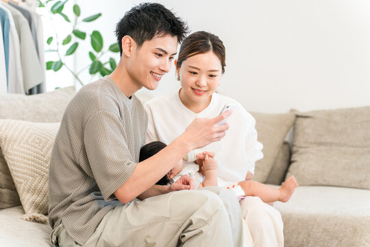 A couple of parents sitting on the sofa looking at their smartphones (apps, online applications, childcare support)