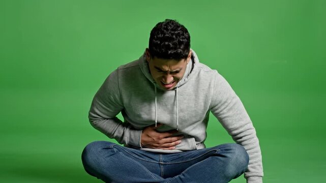Man Crouching With Stomach Pain Isolated On Green Screen Background