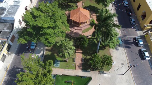 Forward-moving aerial panoramic view of Parque de La Ermita in M&eacute;rida, featuring the pavilion, gardens, and surrounding colonial setting tied to local religious and cultural heritage
