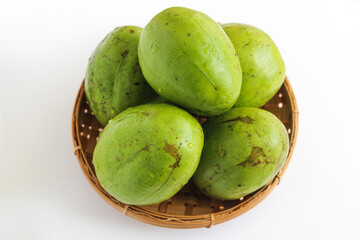 A basket filled with fresh Ambarella (Kedondong) fruits, a tangy, crisp tropical fruit. Isolated on a white background.